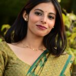 Portrait of a young woman in a green saree with natural backdrop. Traditional elegance outdoors.