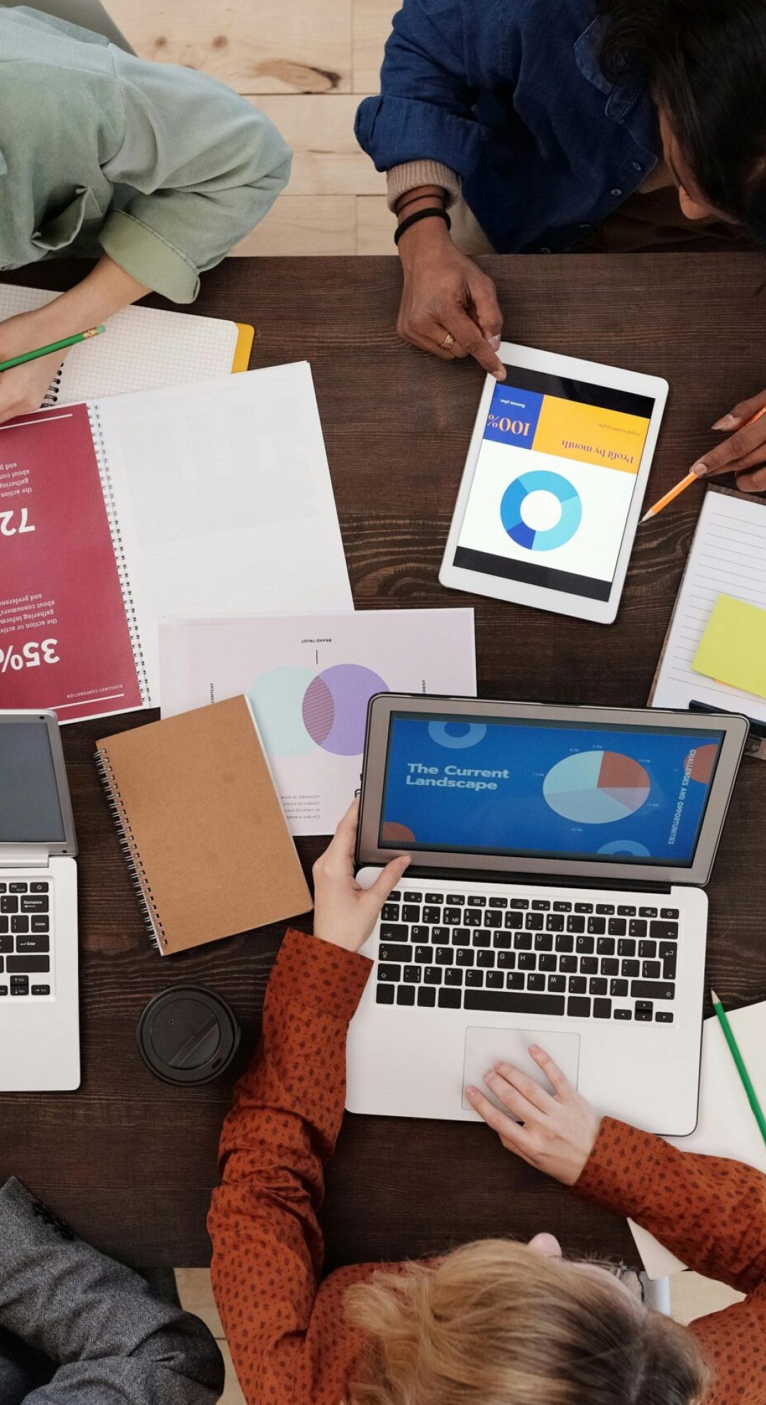 A diverse team collaborating on digital marketing strategies at a desk, using laptops and tablets.